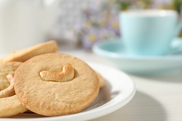 Plate with tasty cashew cookies on white wooden table, closeup. Space for text
