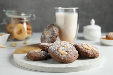 Tasty chocolate cookies with cashew and powdered sugar on white table, closeup