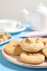Plate with tasty cashew cookies on light blue wooden table, closeup