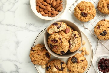 Delicious oatmeal cookies with raisins and nuts on white marble table, flat lay