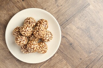 Tasty chocolate puffed rice balls on wooden table, top view. Space for text