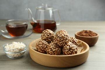 Tasty chocolate puffed rice balls served with tea on wooden table, closeup