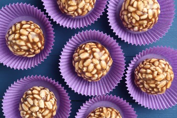 Tasty chocolate puffed rice balls on blue wooden table, flat lay