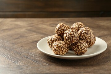 Tasty chocolate puffed rice balls on wooden table, space for text