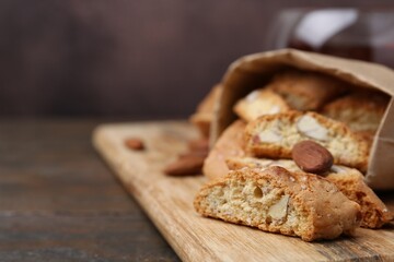 Paper bag with tasty almond biscuits (Cantuccini) and nuts on wooden table, closeup. Space for text