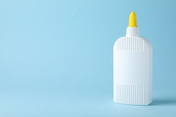 Bottle of glue on light blue background, space for text