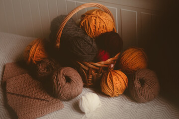 Colorful balls of yarn can be found in a wooden basket at home. These are the materials used for crochet, a hobby