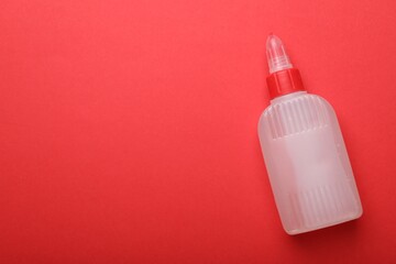 Bottle of glue on red background, top view. Space for text