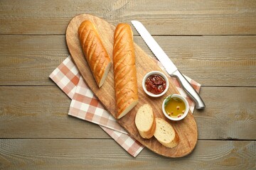 Cut fresh baguette served on wooden table, top view