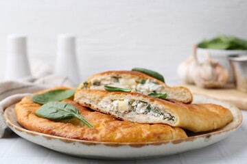 Tasty calzones with basil and cheese on white table, closeup