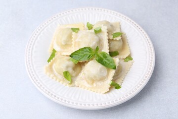 Delicious ravioli with cheese and basil on light table, closeup