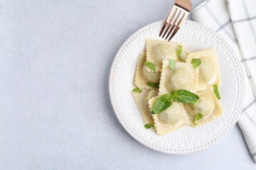 Delicious ravioli with cheese and basil served on light table, top view. Space for text