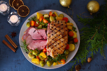 Clove baked ham with potatoes, carrots, turnip and brussel sprouts. Christmas decorations. New Year...