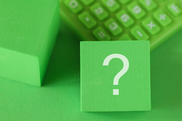 Green Question mark sign on block cube, green calculator on green background. Sustainability  ESG...