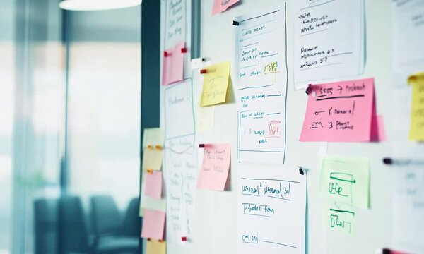 Camera movement captures a project management board adorned with colorful sticky notes and documents, highlighting teamwork and effective organization