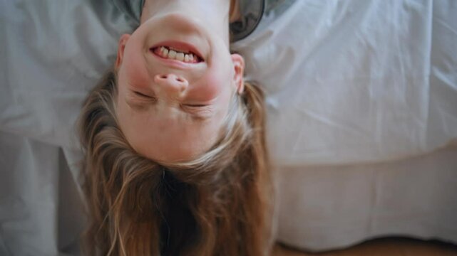 Child girl funny faces lying bed portrait. Cute happy little kid looking camera