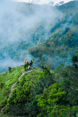 Obraz premium Exploring nature trails hikers on a misty mountain path lush green environment outdoor adventure aerial view serenity and discovery