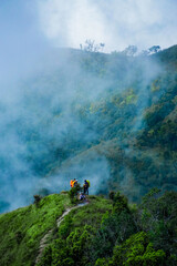 Adventurous hikers overlooking misty mountain landscape scenic nature trail outdoor activity lush green environment bird's eye view exploration