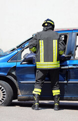 firefighter with protective helmet during emergency response on blue car involved in car accident