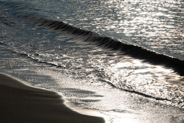 Licht und Schatten - sanfte Brandung am Strand im Gegenlicht