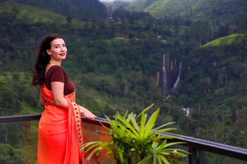 A beautiful girl in a sari against the background of a waterfall. Sri Lanka