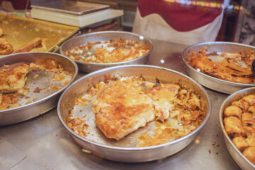 traditional Burek pastry displayed on metal trays at a bustling street market in the early afternoon