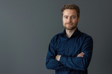 Obraz premium A person standing with their arms crossed, set against a neutral gray backdrop