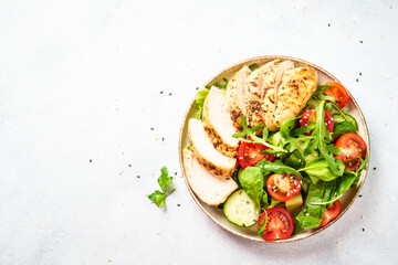 Chicken salad with grilled meat and vegetables at black table. Top view with copy space.