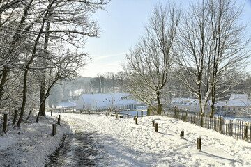Fototapeta premium Chemin à pavés descendant vers le domaine de l'abbaye du Rouge-Cloître sous la neige à Auderghem 