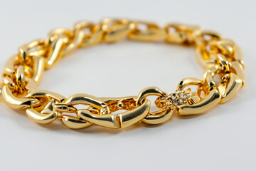 Fototapeta premium A gold chain bracelet with a diamond clasp. A gold chain with a gray background. Chain gold gray background decoration lies. A gold chain lying on a gray background with gold lifestyle decorations.