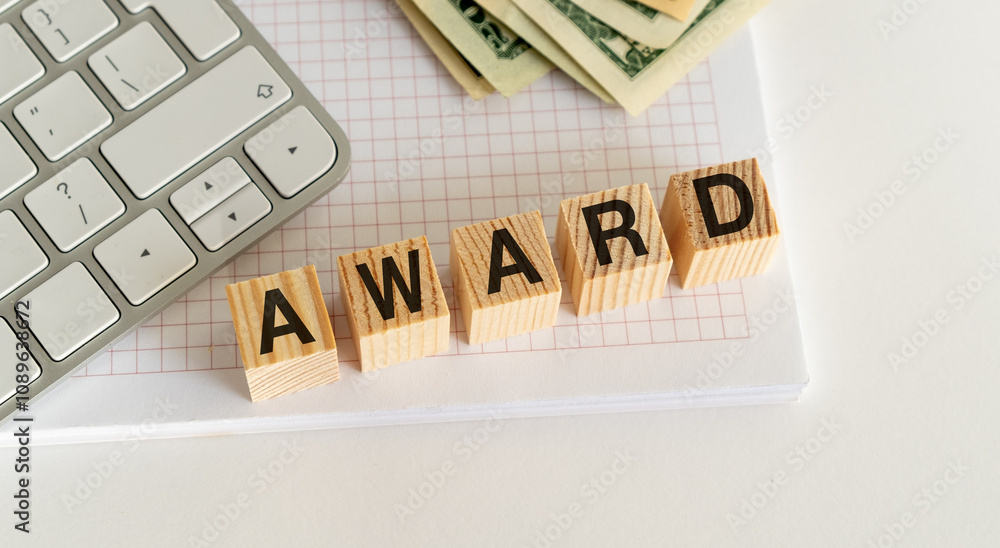 Poster wooden blocks with the word award on notebook with keyboard and money in the background.