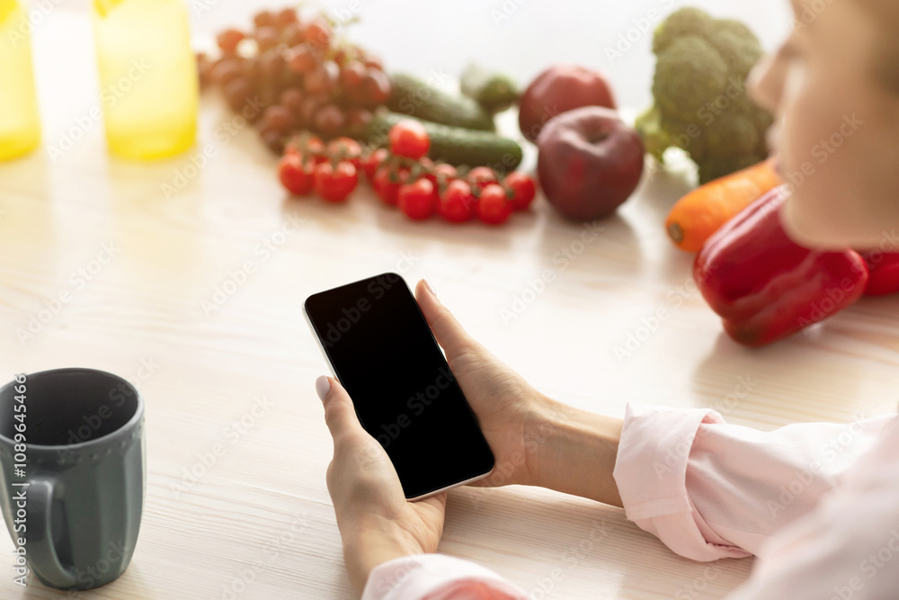Poster search recipe. over the shoulder view of young lady holding and using smartphone with blank black em