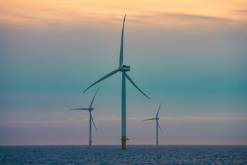 Wind turbines in the sea during colourful sunset sky.