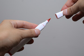 Detailed Image of a Person's Hands Removing the Cap from a Red Marker Pen, Highlighting the Marker...