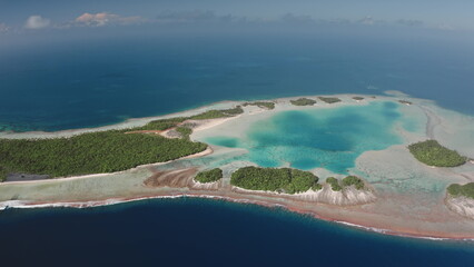 Aerial drone view of Rangiroa atoll showing the turquoise lagoon, coral reefs, and forested motus,...