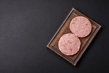 Naklejka premium Raw chicken burger cutlet with salt, spices and herbs