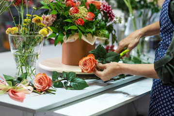 The hands of florist, making bouquets and flower arrangements. Woman collecting a bouquet of...