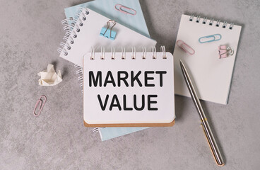 Market Value text on a paper with pen and notebook on grey background