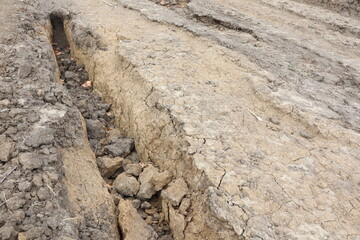 The cracked and dry earth terrain reveals significant geological features and formations