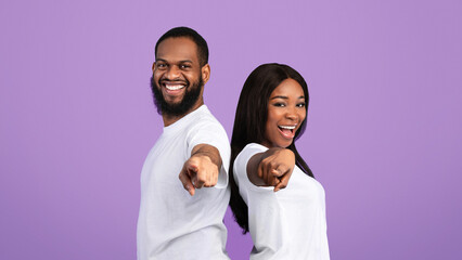 And What's About You. Portrait Of Excited African American Young Couple Pointing Fingers At Camera, Happy Man And Woman Choosing You, Standing Back To Back Isolated Over Blue Studio Background