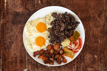 Traditional Brazilian everyday food, black bean stew, bacon, egg, salad, pickles. Real rustic food