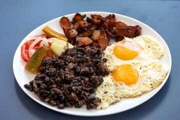 Traditional Brazilian everyday food, black bean stew, bacon, egg, salad, pickles. Real rustic food
