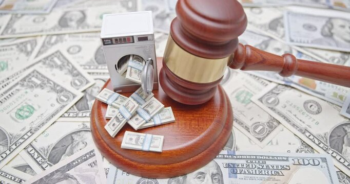 Money laundering, financial crimes, corruption, legal enforcement and economic justice : A judge gavel, a miniature washing machine overflowing with bundles of money, and dollar bill scattered beneath