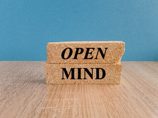 Brick blocks with the expression open mind. Beautiful wooden table, blue background. Business open...