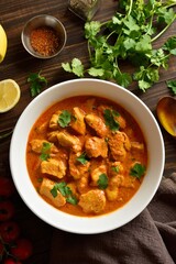  Indian dish chicken tikka masala in bowl on wooden background