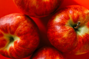 Close-up of vibrant red apples against a matching red background, highlighting their texture, color, and natural freshness in a bold, minimalistic composition