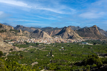 Naklejka premium Panoramic view of the orchard of the Ricote valley, Region of Murcia, Spain, with the town in the background and the mountains on a sunny day