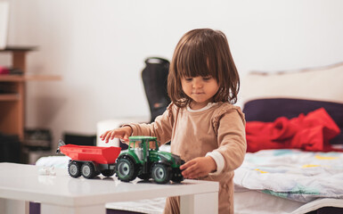 A little girl is playing with a tractor toy

