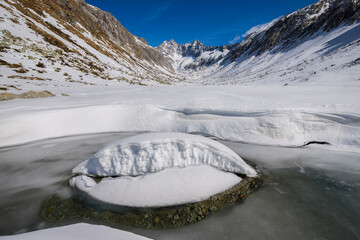 Scenic landscape of snowy winter scenery with soft snow by river in Italian alps, Adamello Park, Lombardy, Italy