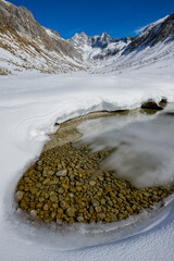Scenic landscape of snowy winter scenery with snow and frozen river in Italian alps, Adamello Park, Lombardy, Italy